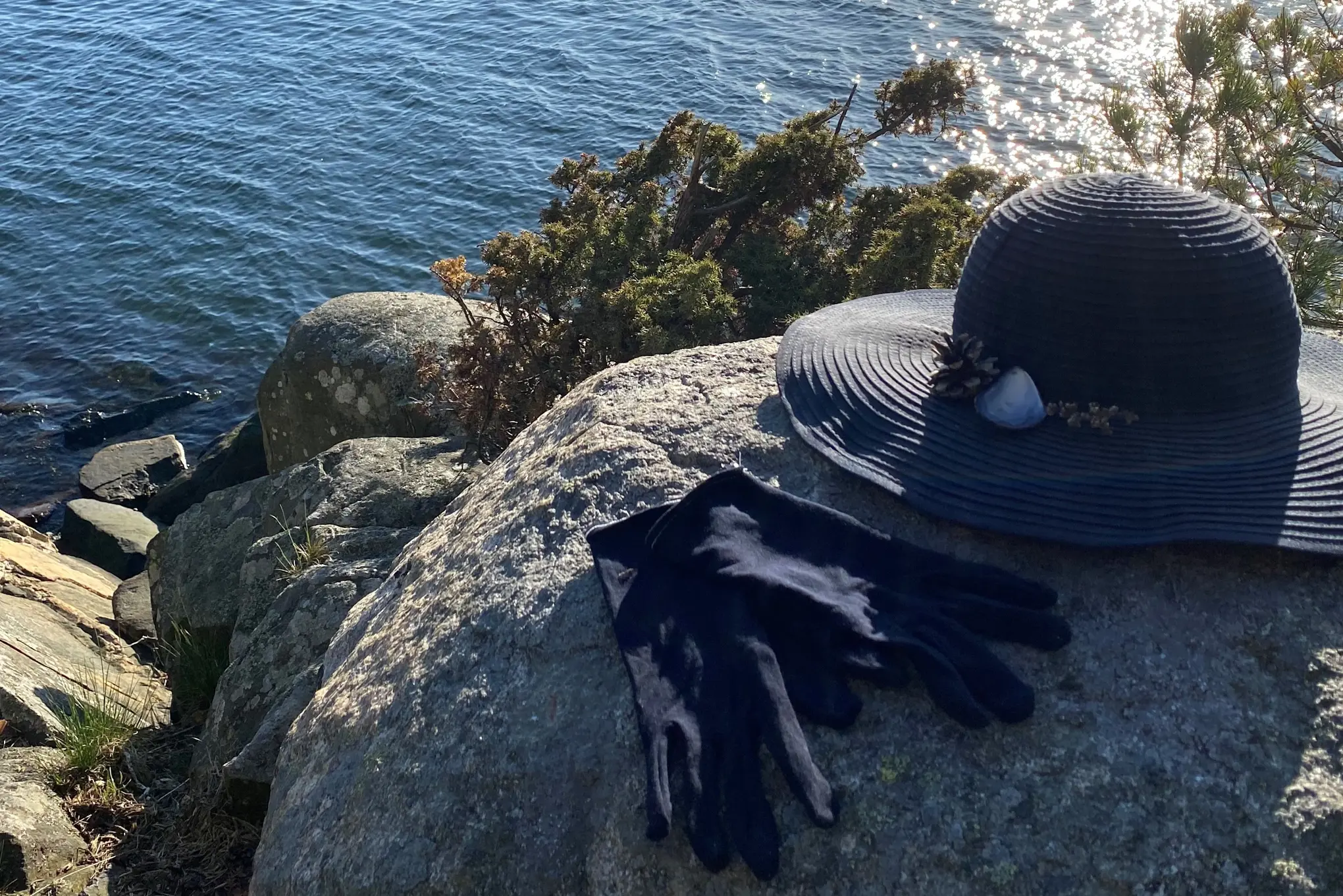 En hatt og hansker på en stein ved vann